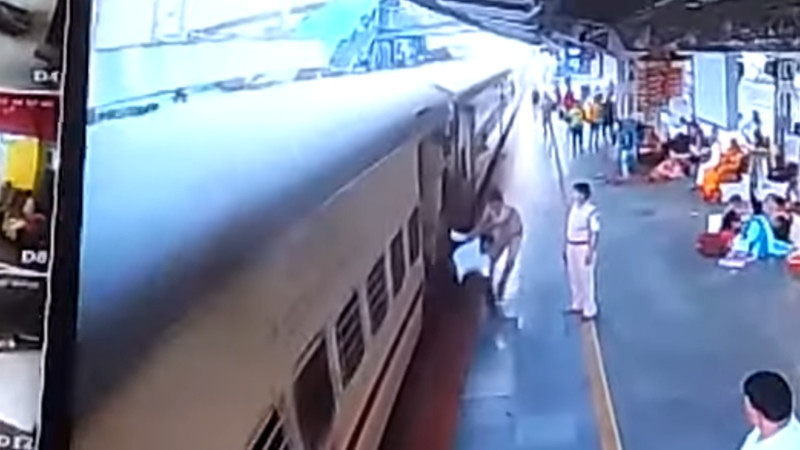 電車から飛び降りようとした男性を助ける警官。