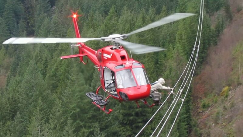 ヘリコプターで電気の通った送電線の作業中。