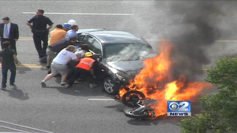 【全米が震撼】炎上する車の下敷きになったバイク運転手を救助する決死の連携をご覧下さい